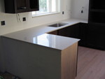 The counter with the sink in place. They still need to cut holes in the counter top for things like the faucet. The bare wood will be covered by a vertical slab like on the other cabinet.