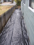For some reason the side yard is nor covered in plastic. It could be a weed barrier, or hiding some nasty chemical spill.